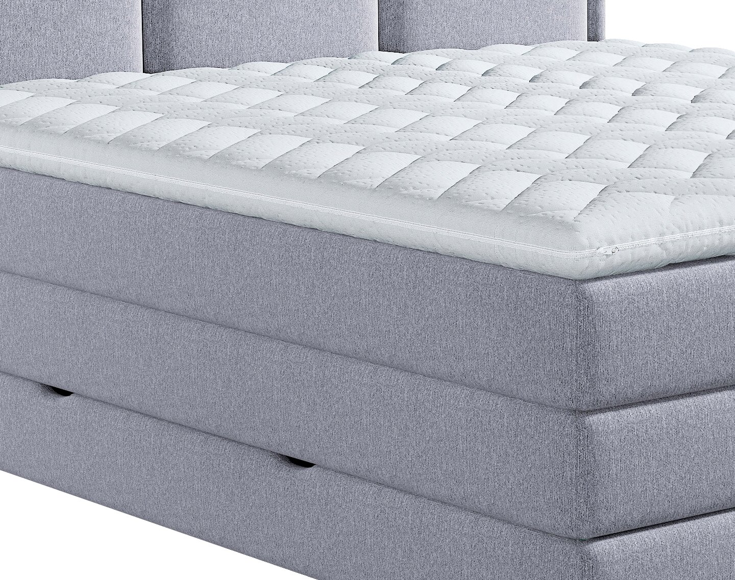 Close-up in schuin vooraanzicht van een wit, gewatteerd topmatras met ritssluiting op een lichtgrijs gestoffeerd boxspringbed