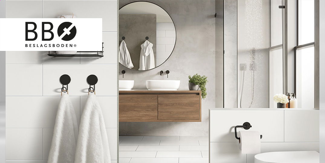 Helles Badezimmer mit zwei Keramikbecken auf einem Holunterschrank und einem runden Spiegel. Logo des Herstellers Beslagsboden