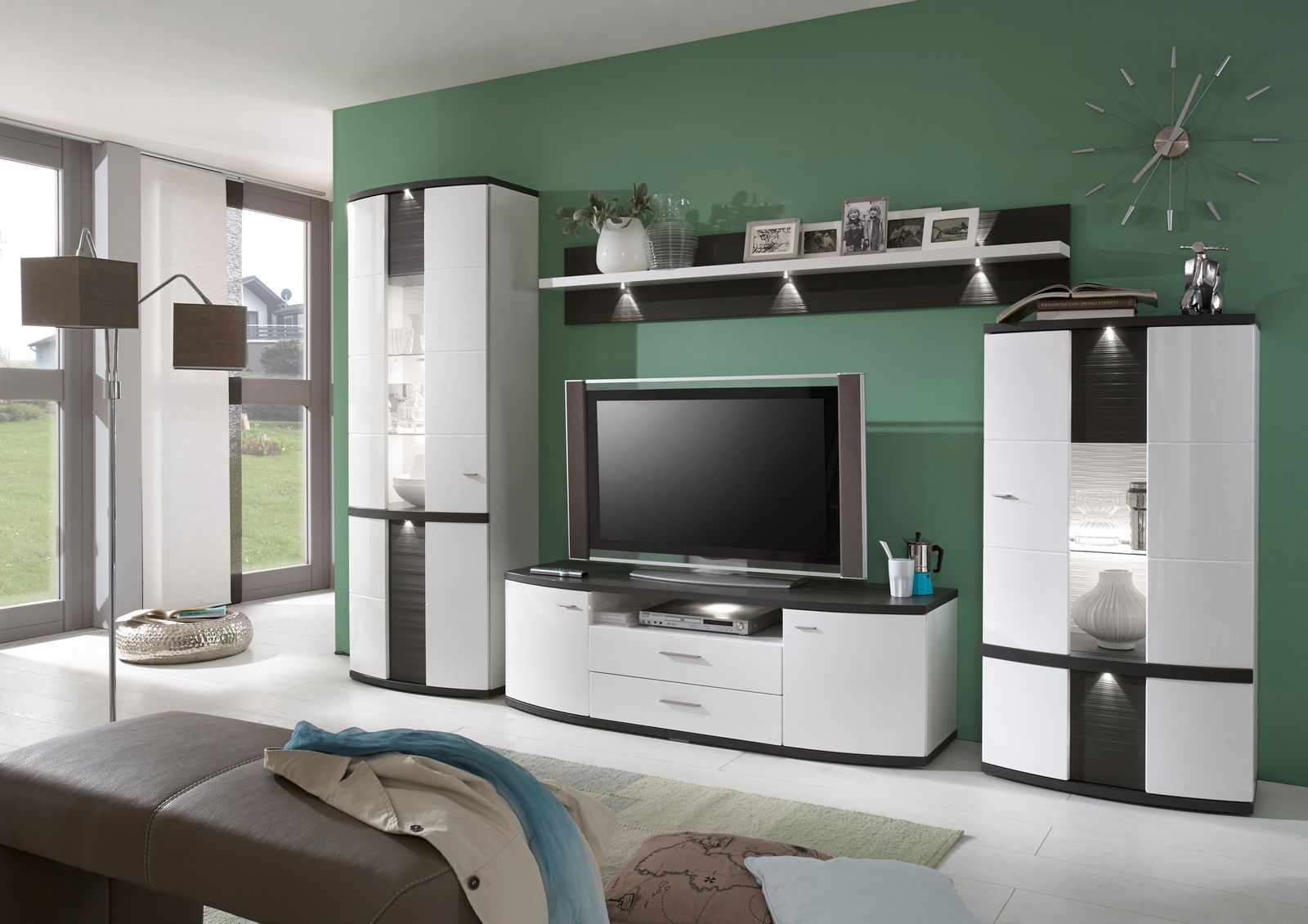 Moderne Wohnzimmer-Wandkombination in Weiß und Schwarz mit TV-Schrank, Vitrinen und Wandregal, seitliche Perspektive.