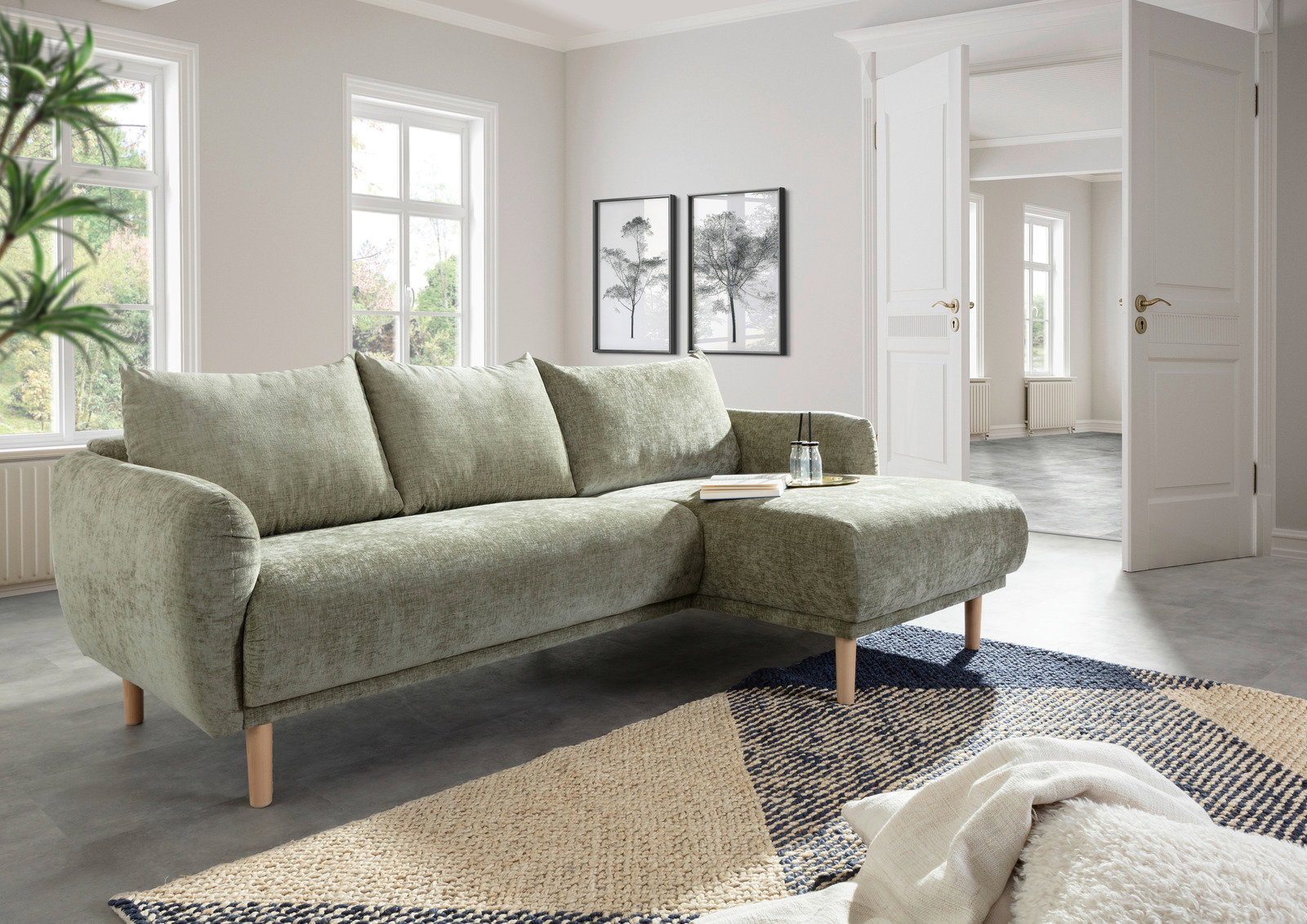Grünes Ecksofa mit Holzfüßen in einem modernen Wohnzimmer, seitliche Perspektive