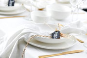 Eleganter Speiseteller Skagen 30,5 cm, von oben fotografiert, auf einem gedeckten Tisch mit weißem Tischtuch und goldfarbenem Besteck, dekoriert mit einer Serviette und einem Namensschild.