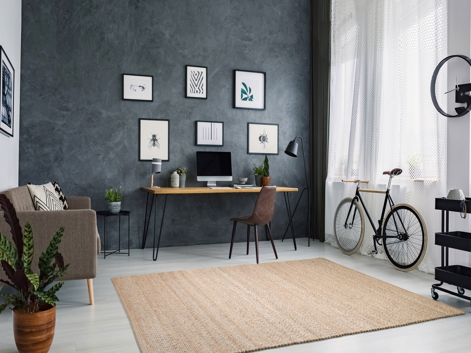 Handgewebter Teppich in einem modernen Wohnzimmer mit grauer Wand, Schreibtisch, Stuhl und Fahrrad, aus der Vogelperspektive betrachtet.