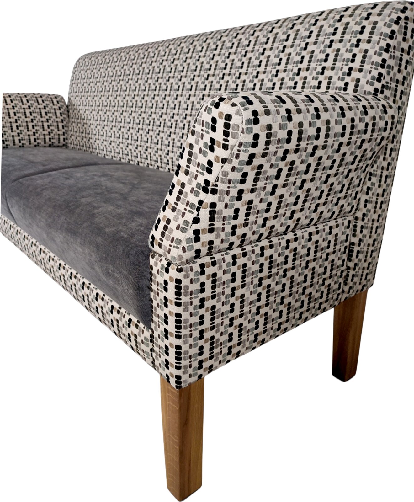 Nahaufnahme eines gepolsterten Sofas mit gemustertem Stoff in Schwarz/Grau/Beige, grauer Sitzfläche und Holzbeinen, gezeigt aus schräger Vorderseitenperspektive mit Fokus auf Armlehne und Rückenlehne