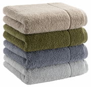 Gestapelte Handtücher in verschiedenen Farben, von oben nach unten: beige, olivgrün, dunkelgrau und hellgrau, seitliche Perspektive.