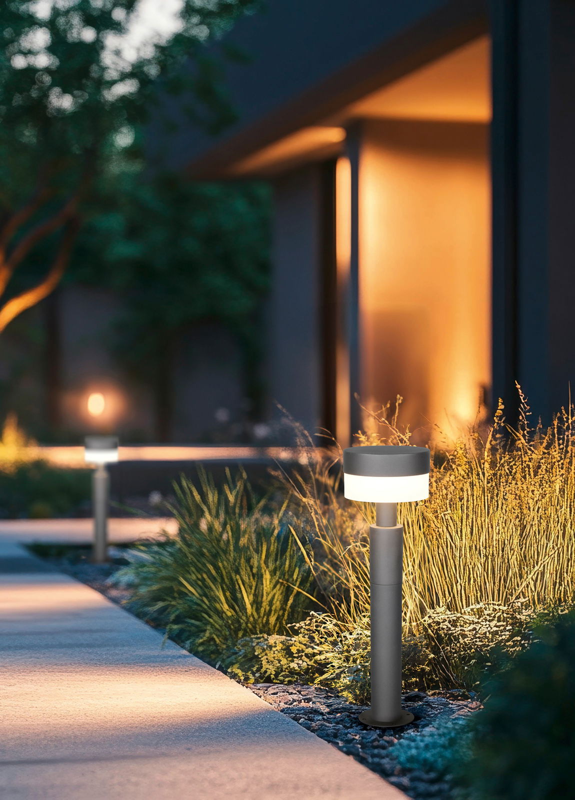 Moderne LED-Pollerleuchte in einem Garten bei Dämmerung, seitliche Perspektive