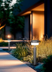 Moderne LED-Pollerleuchte in einem Garten bei Dämmerung, seitliche Perspektive