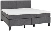 Graues Boxspringbett mit gepolstertem Kopfteil, seitliche Perspektive