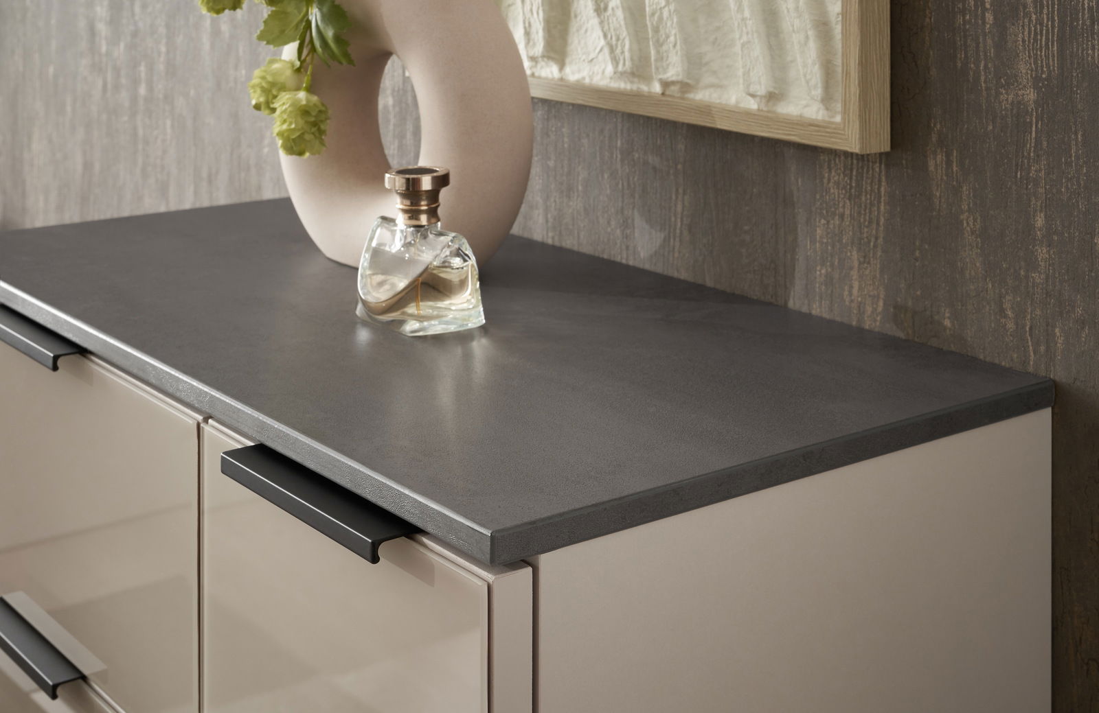 Nahaufnahme eines Highboards mit dunkler Arbeitsplatte, dekoriert mit einer Vase und einem Parfümflakon, seitliche Perspektive