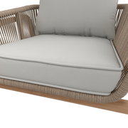 Nahaufnahme eines Lounge-Sessels mit hellgrauen Kissen und einem Rahmen aus geflochtenem Seil, seitliche Perspektive.