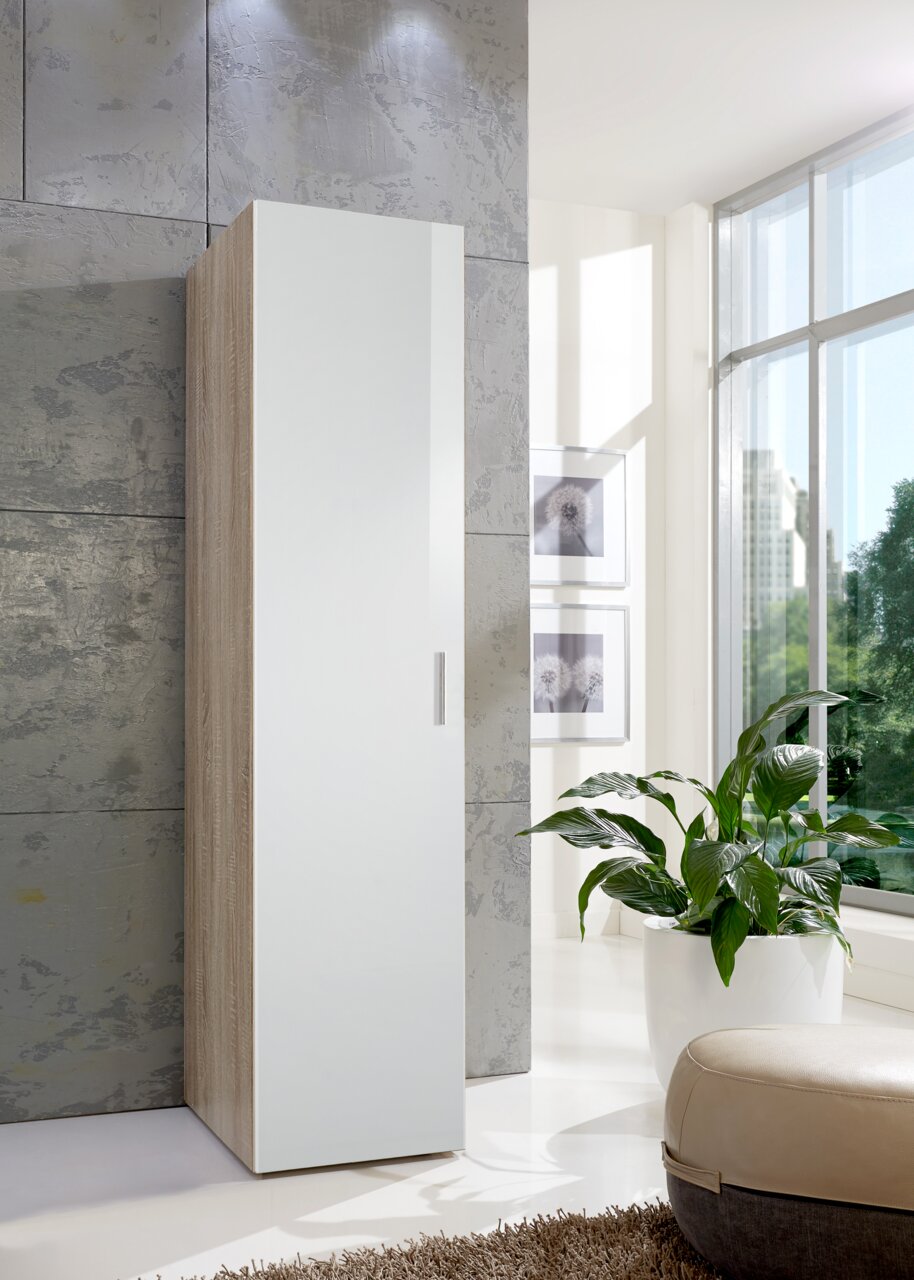 Moderne multifunctionele kast in houtlook met witte deur, gezien vanaf de zijkant, in een lichte ruimte met grote ramen en planten.