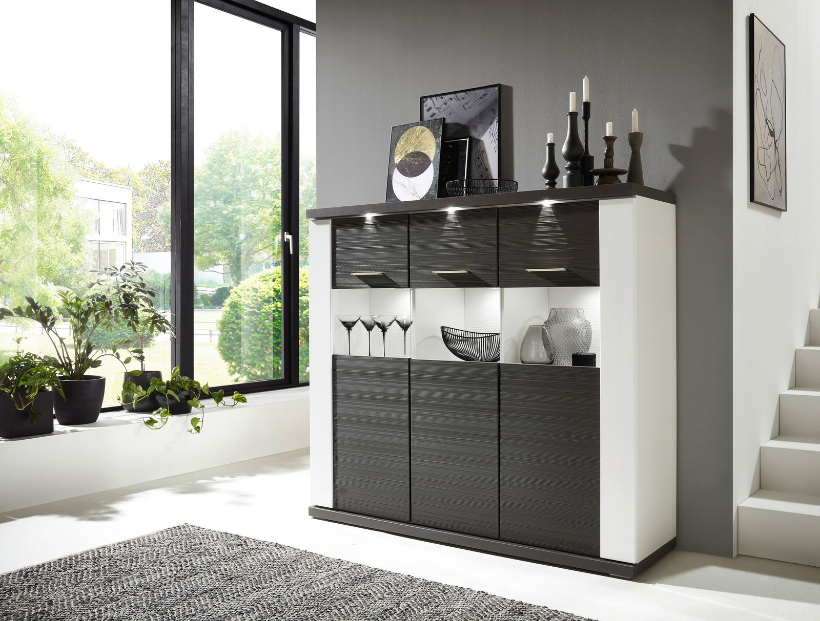 Modernes Highboard in dunklem Holz mit integrierter Beleuchtung, dekoriert mit Vasen und Kerzenhaltern, seitliche Perspektive