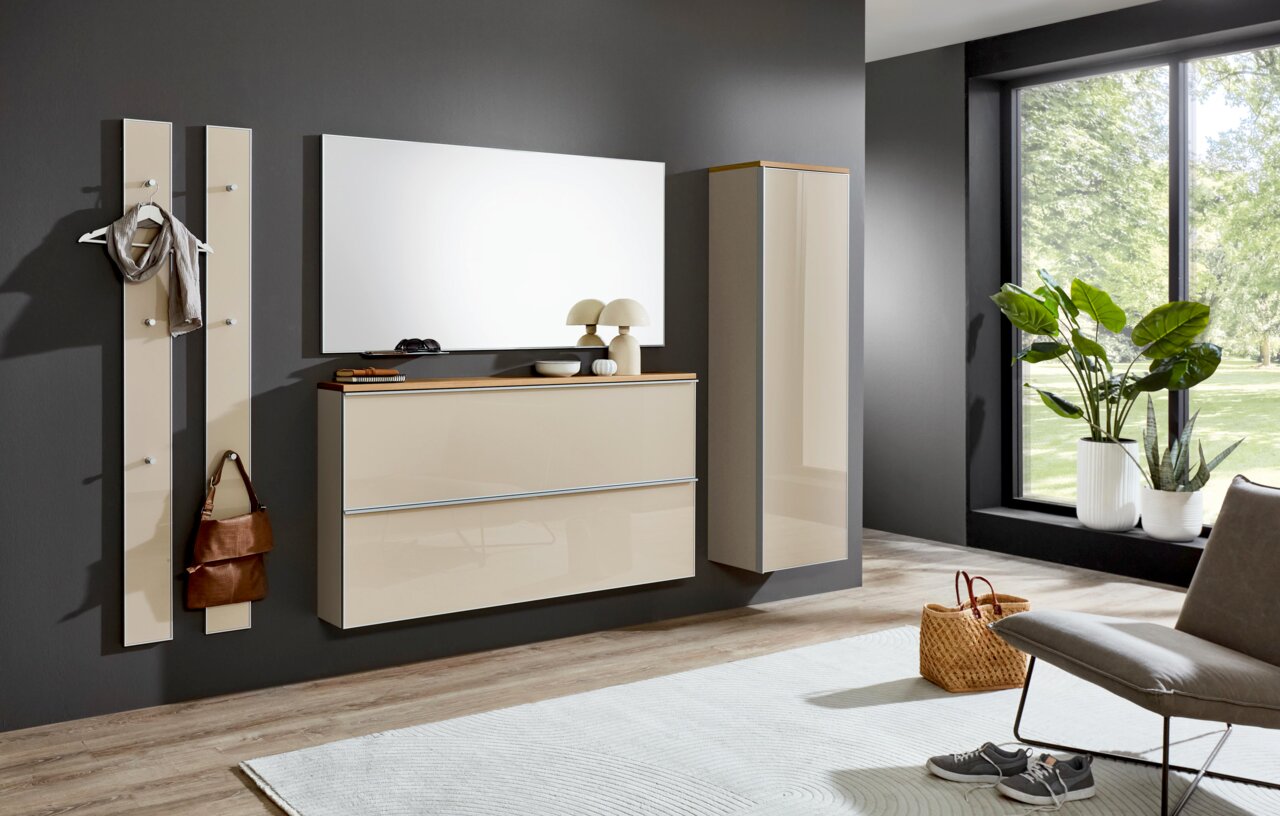 Modernes Flurmöbel-Set in Beige mit Hochglanzfronten: Wandgarderobenpaneele, hängende Kommode mit Holzablage, großer Spiegel und Hängeschrank an dunkelgrauer Wand, perspektivisch in leichter Schrägansicht von vorn.