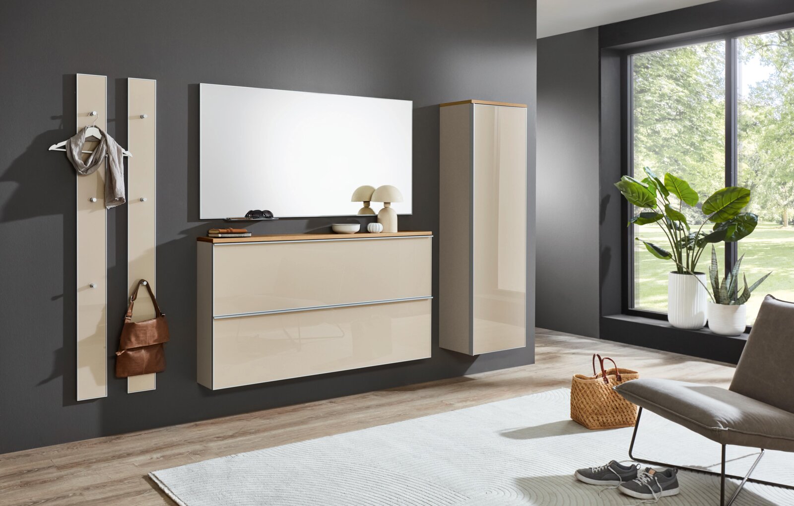 VOSS Hängegarderobenschrank re. VORTINA Modernes Flurmöbel-Set in Beige mit Hochglanzfronten: Wandgarderobenpaneele, hängende Kommode mit Holzablage, großer Spiegel und Hängeschrank an dunkelgrauer Wand, perspektivisch in leichter Schrägansicht von vorn.