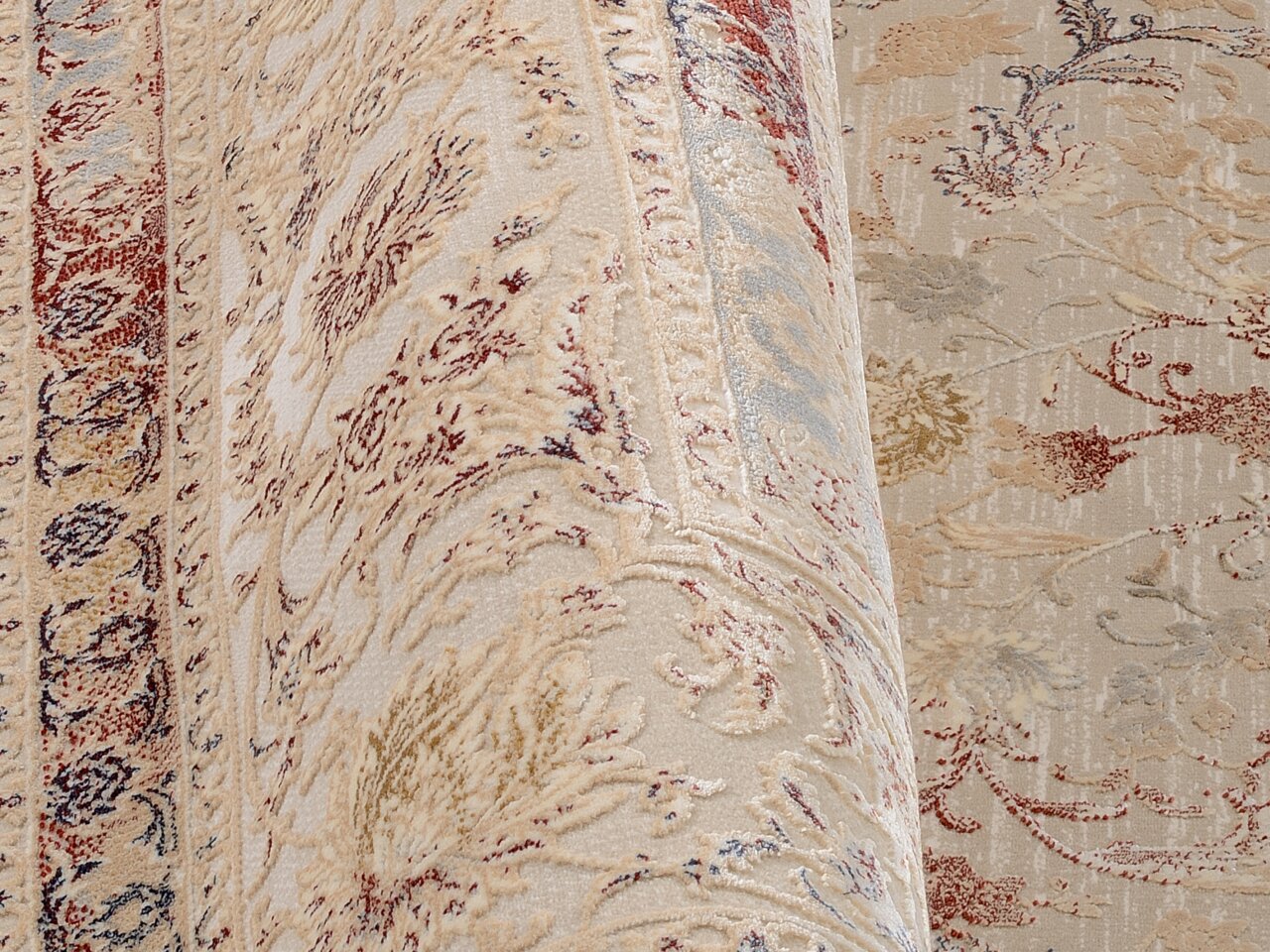 Nahaufnahme eines Orientteppichs mit floralen Mustern in Beige, Rot und Blau. Der Teppich ist teilweise aufgerollt und zeigt eine detaillierte Textur.
