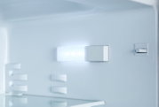 Innenansicht eines Kühlschranks mit eingeschalteter LED-Innenbeleuchtung und Glasablage, frontale Perspektive