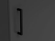 Nahaufnahme eines schwarzen Griffs an einer dunkelgrauen Kommodentür, seitliche Perspektive