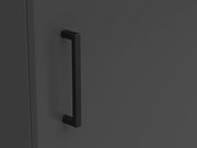 Nahaufnahme eines schwarzen Griffs an einer dunkelgrauen Kommodentür, seitliche Perspektive