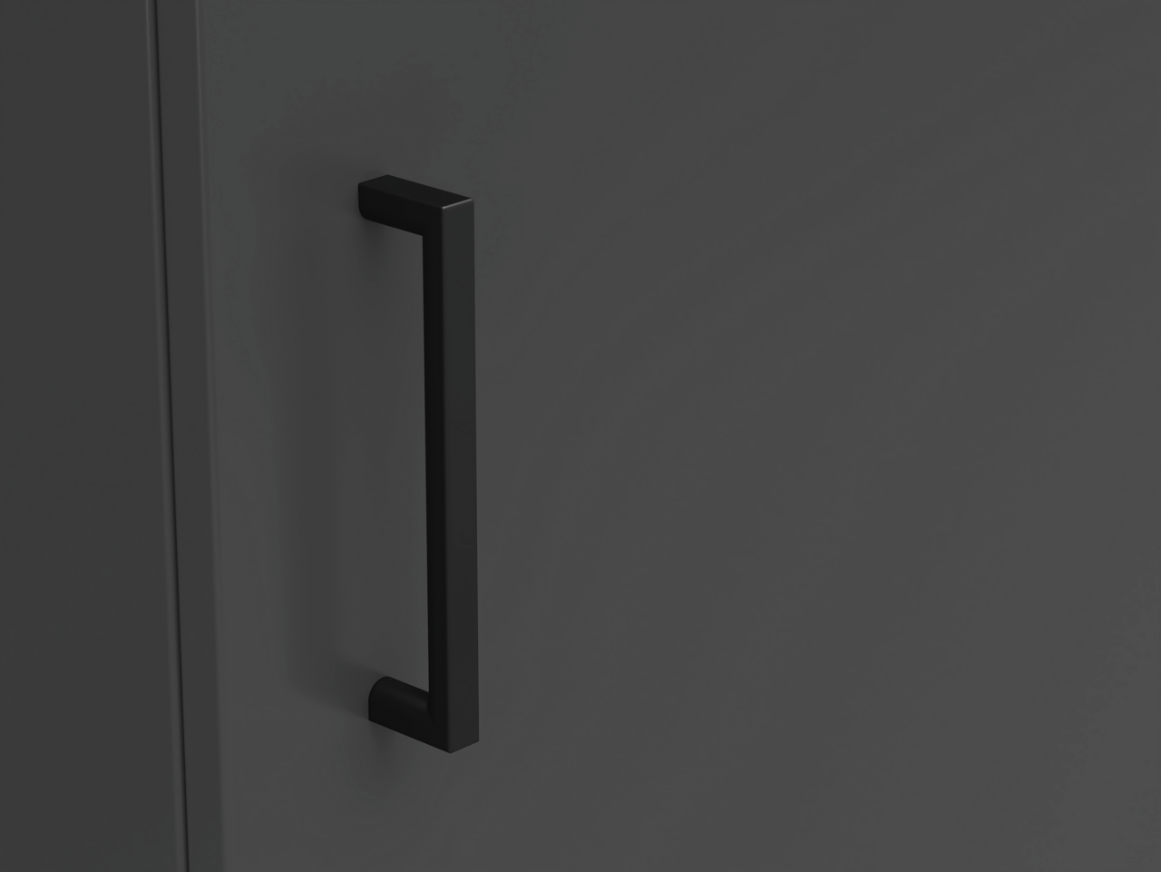 Nahaufnahme eines schwarzen Griffs an einer dunkelgrauen Kommodentür, seitliche Perspektive