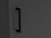 Nahaufnahme eines schwarzen Griffs an einer dunkelgrauen Kommodentür, seitliche Perspektive