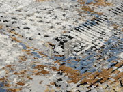 Nahaufnahme eines Designer-Teppichs mit abstraktem Muster in Blau-, Grau- und Brauntönen, von schräg oben fotografiert.