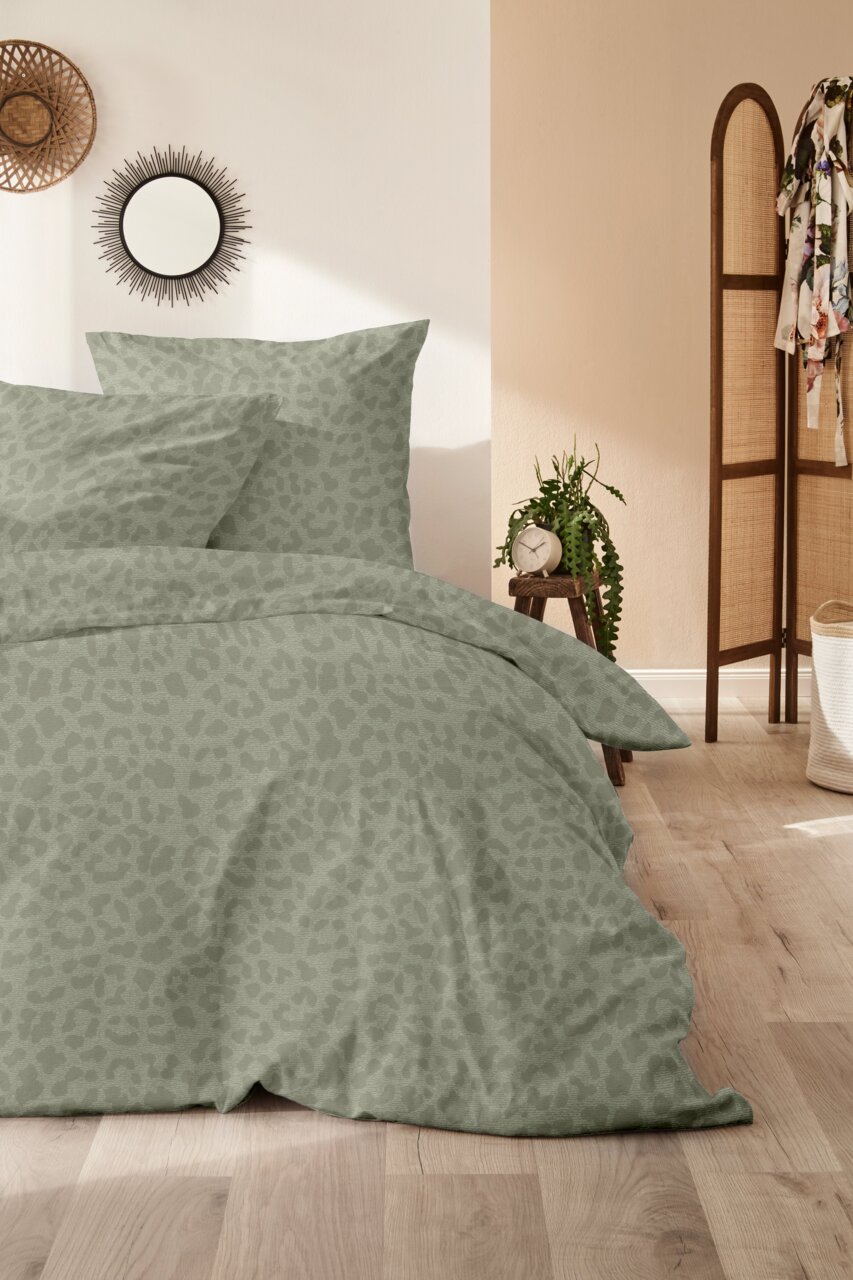 Bettwäsche-Set in sanftem Grün mit dezentem Muster, auf einem Bett in einem stilvoll eingerichteten Schlafzimmer, aus der Vorderansicht fotografiert.