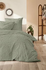 Bettwäsche-Set in sanftem Grün mit dezentem Muster, auf einem Bett in einem stilvoll eingerichteten Schlafzimmer, aus der Vorderansicht fotografiert.