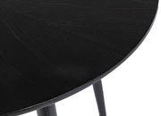 Nahaufnahme eines schwarzen runden Esstisches mit sichtbarer Holzmaserung, Perspektive von oben.