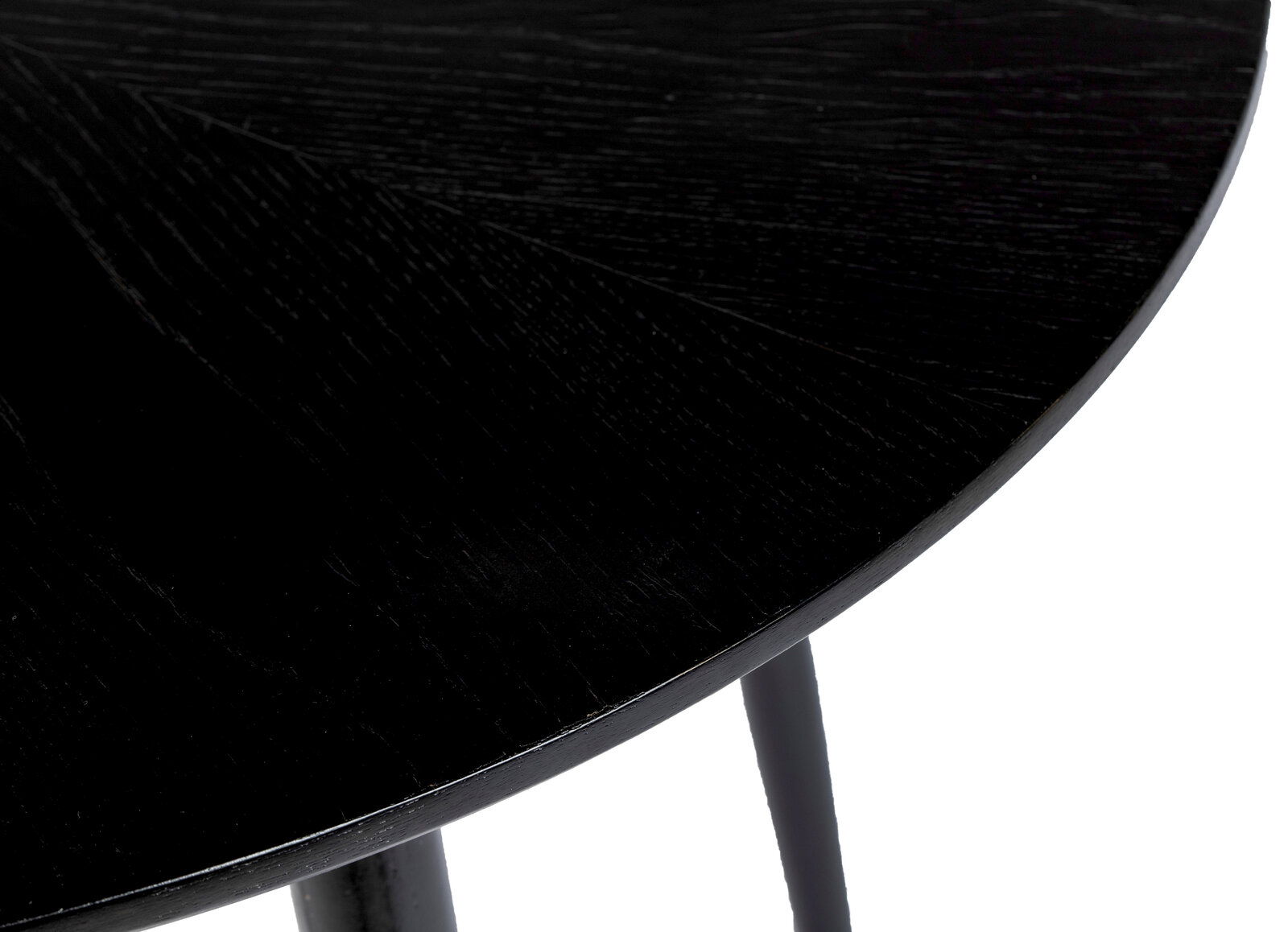 Nahaufnahme eines schwarzen runden Esstisches mit sichtbarer Holzmaserung, Perspektive von oben.