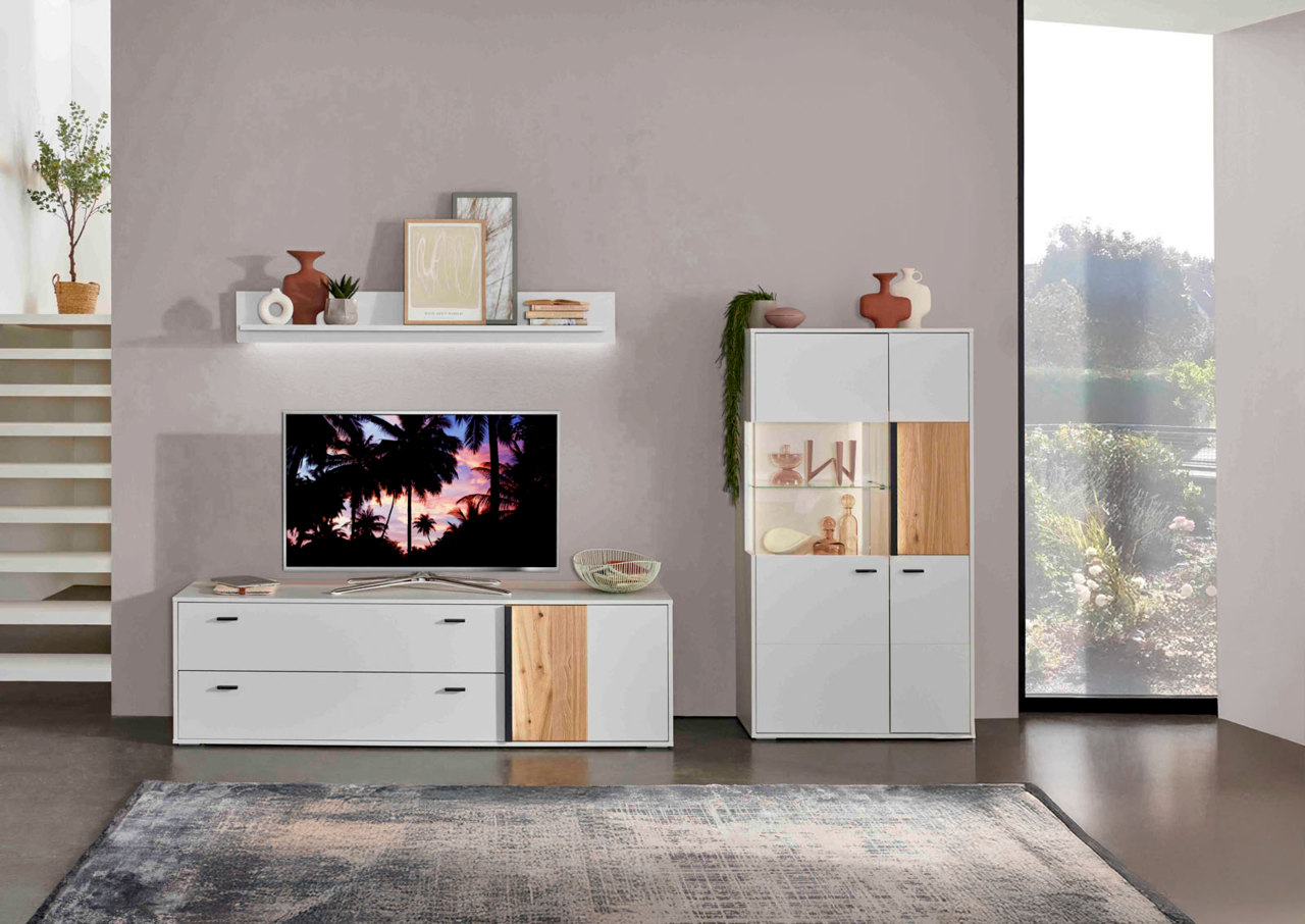Wohnzimmeransicht mit modernem TV-Lowboard, Wandboard und Highboard in Weiß mit Holzakzenten, dekoriert mit Vasen und Pflanzen, seitliche Perspektive.