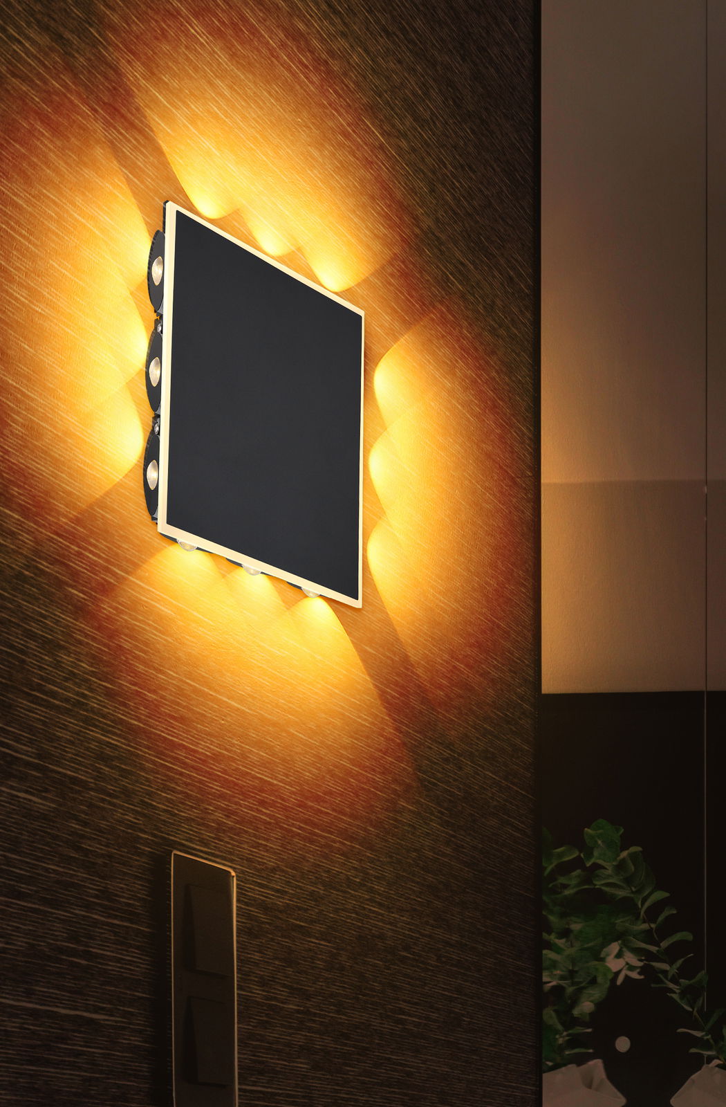 Moderne Wandleuchte SAIDY mit rechteckigem Design, seitlich beleuchtet, an einer strukturierten Wand montiert, seitliche Perspektive.