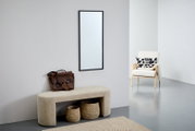 Rechthoekige spiegel met zwarte lijst, hangend aan een lichtgrijze muur, in een moderne woonkamer met bank, mand en fauteuil. Perspectief: vooraanzicht.