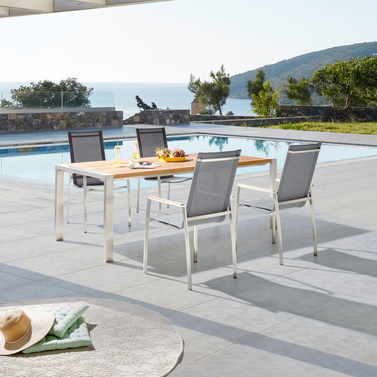 Moderne tuinstoel Amatio CHUR op een terras met uitzicht op een zwembad en de zee, zijaanzicht.