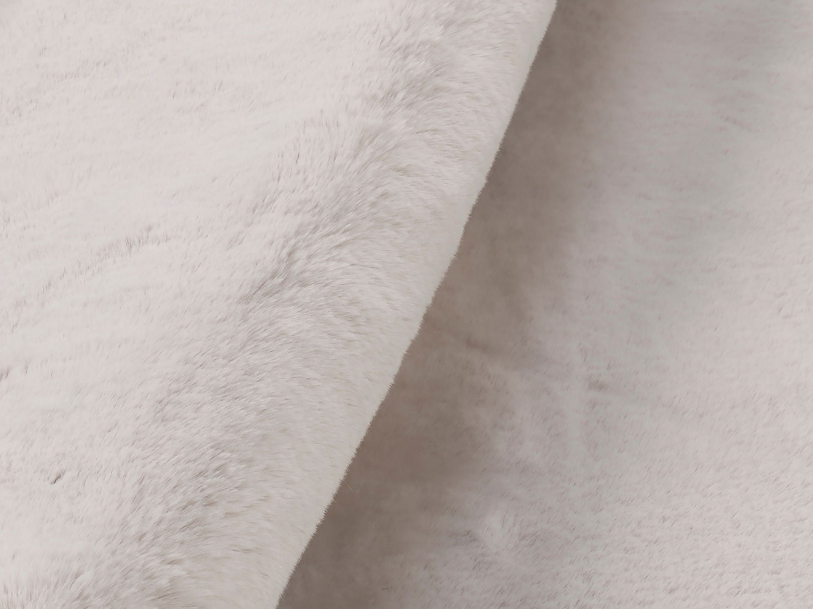 Nahaufnahme eines weißen Fellteppichs mit weicher, flauschiger Textur, seitliche Perspektive