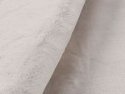 Nahaufnahme eines weißen Fellteppichs mit weicher, flauschiger Textur, seitliche Perspektive