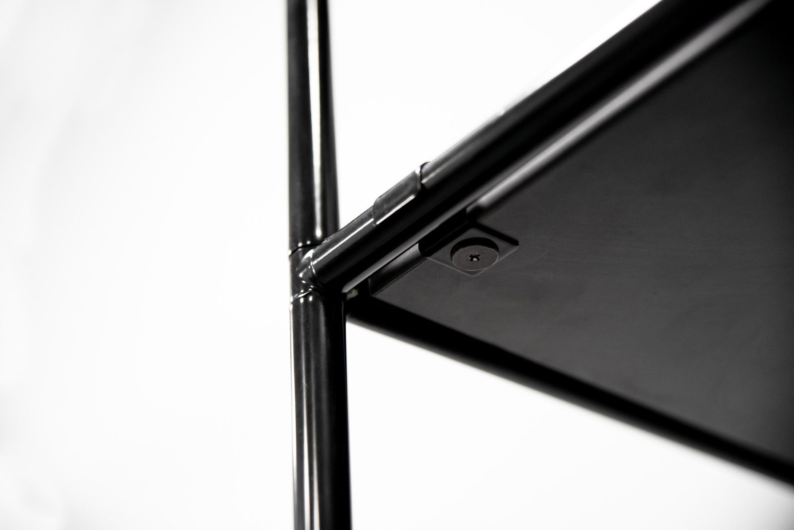 Nahaufnahme eines schwarzen Metallregals mit Fokus auf die Verbindungselemente und Schrauben, seitliche Perspektive.