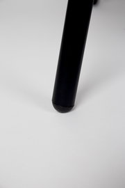 Nahaufnahme eines schwarzen Stuhlbeins auf weißem Hintergrund, Perspektive von unten.