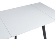 Witte eettafel met strakke lijnen en zwarte poten, gefotografeerd vanuit vogelperspectief.