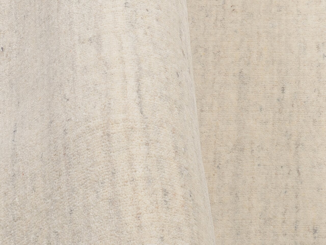 Nahaufnahme eines hellen Wollteppichs mit dezenter Textur, seitliche Perspektive