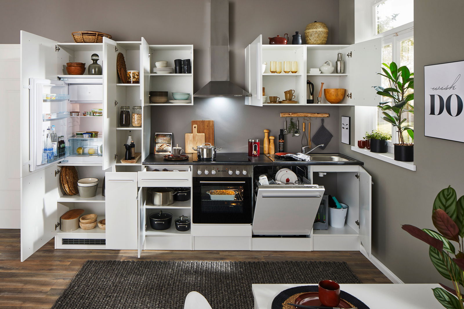 Moderne Küchenzeile in Weiß mit offenen Schränken, Kühlschrank, Herd und Spülmaschine, aus der Frontperspektive fotografiert.