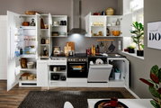 Moderne Küchenzeile in Weiß mit offenen Schränken, Kühlschrank, Herd und Spülmaschine, aus der Frontperspektive fotografiert.