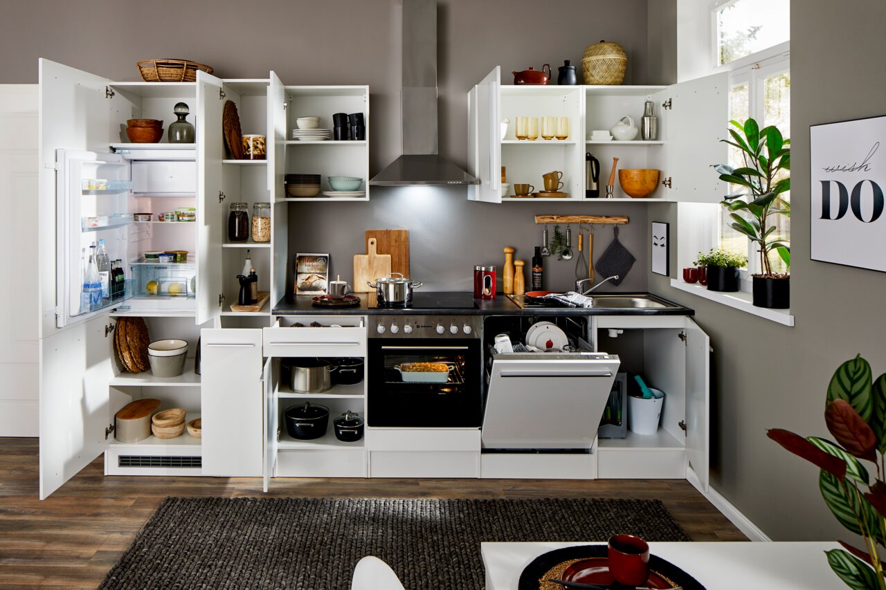 Moderne Küchenzeile in Weiß mit offenen Schränken, Kühlschrank, Herd und Spülmaschine, aus der Frontperspektive fotografiert.