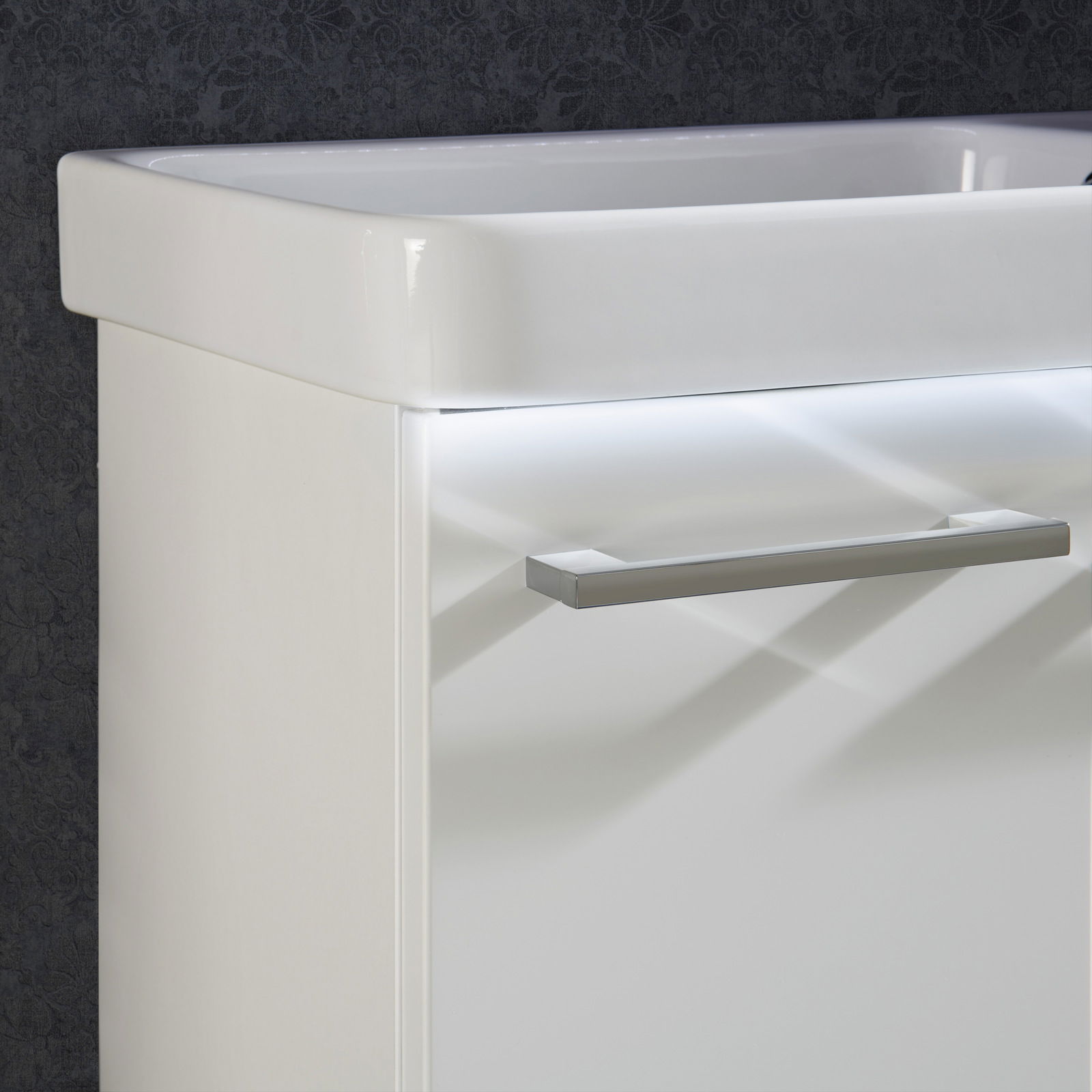 Nahaufnahme eines modernen weißen Waschtisch-Sets mit glänzendem Griff, seitliche Perspektive.