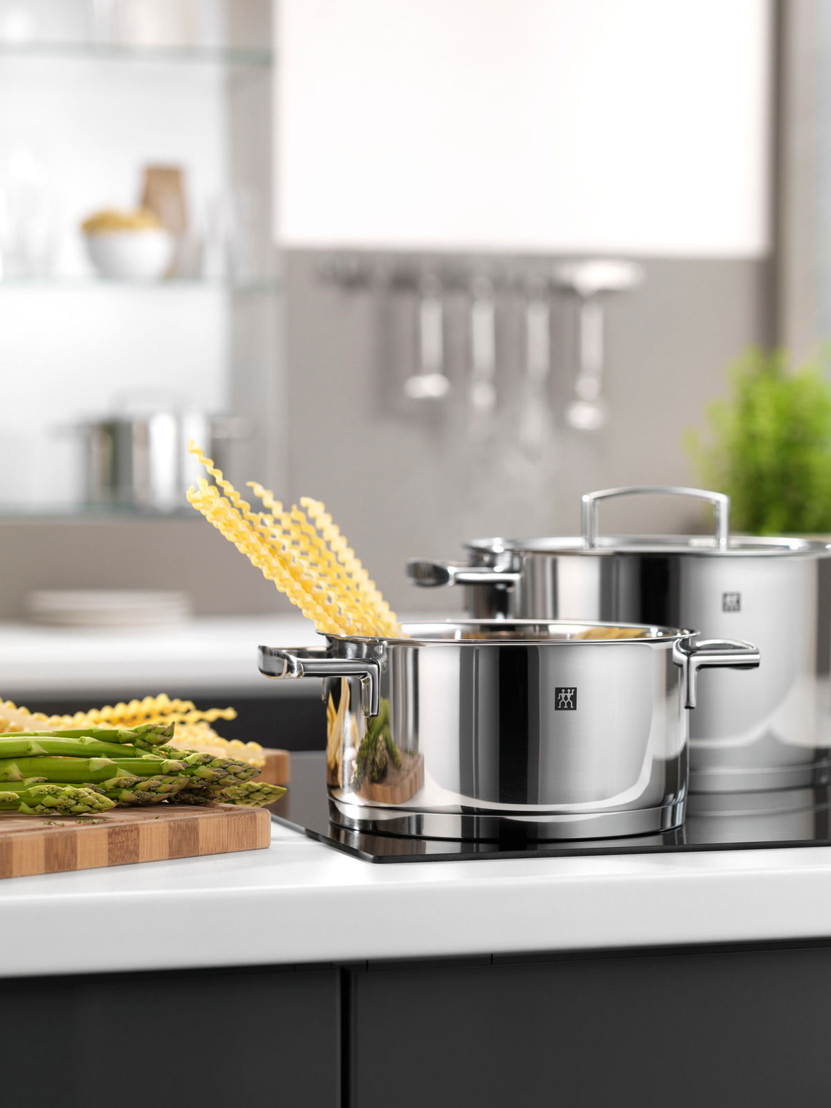 Topfset 5-teilig Passion aus Edelstahl, in moderner Küche auf Herdplatte, mit Spargel und Pasta, seitliche Perspektive