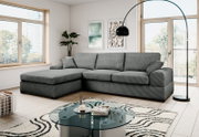 Modernes graues Ecksofa mit linksseitiger Ottomane und drei Sitzkissen in hellem Wohnzimmer, Frontansicht leicht schräg von vorn.