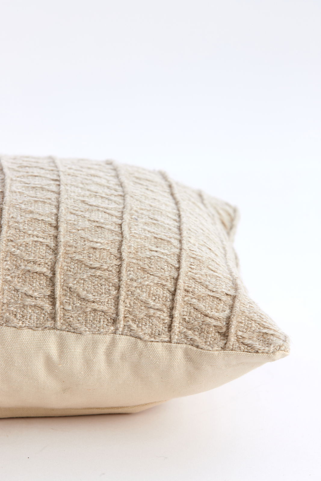 Nahaufnahme eines beigen Kissens mit gestricktem Muster, seitliche Perspektive