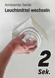 Hand wechselt Leuchtmittel in LED Aufbauleuchte, Perspektive von unten