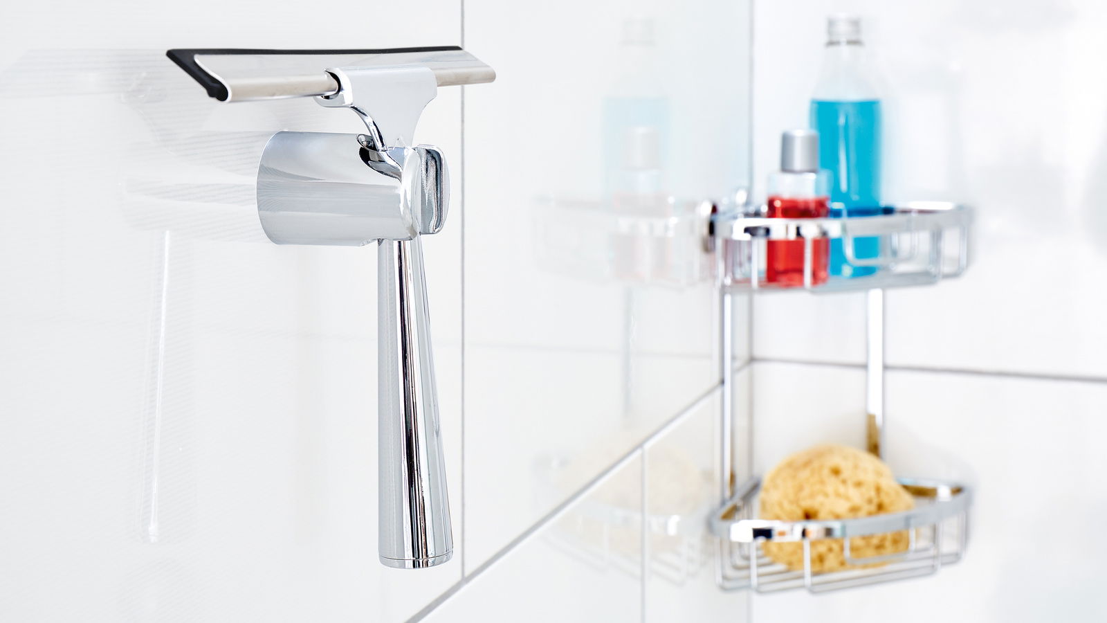 Moderner Duschwischer aus Edelstahl, an einer weißen Badezimmerwand montiert, mit einem Duschkorb im Hintergrund. Seitliche Perspektive.