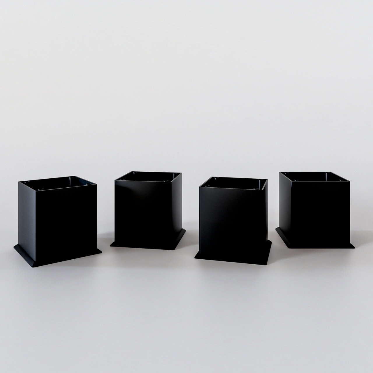 Vier schwarze, quadratische Metallfüße für einen Unterschrank, frontal betrachtet.