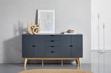 Modernes Sideboard in dunklem Blau mit Holzbeinen, frontal fotografiert. Dekoriert mit einer abstrakten Skulptur, einem gerahmten Kunstwerk und einer Schale auf Büchern.