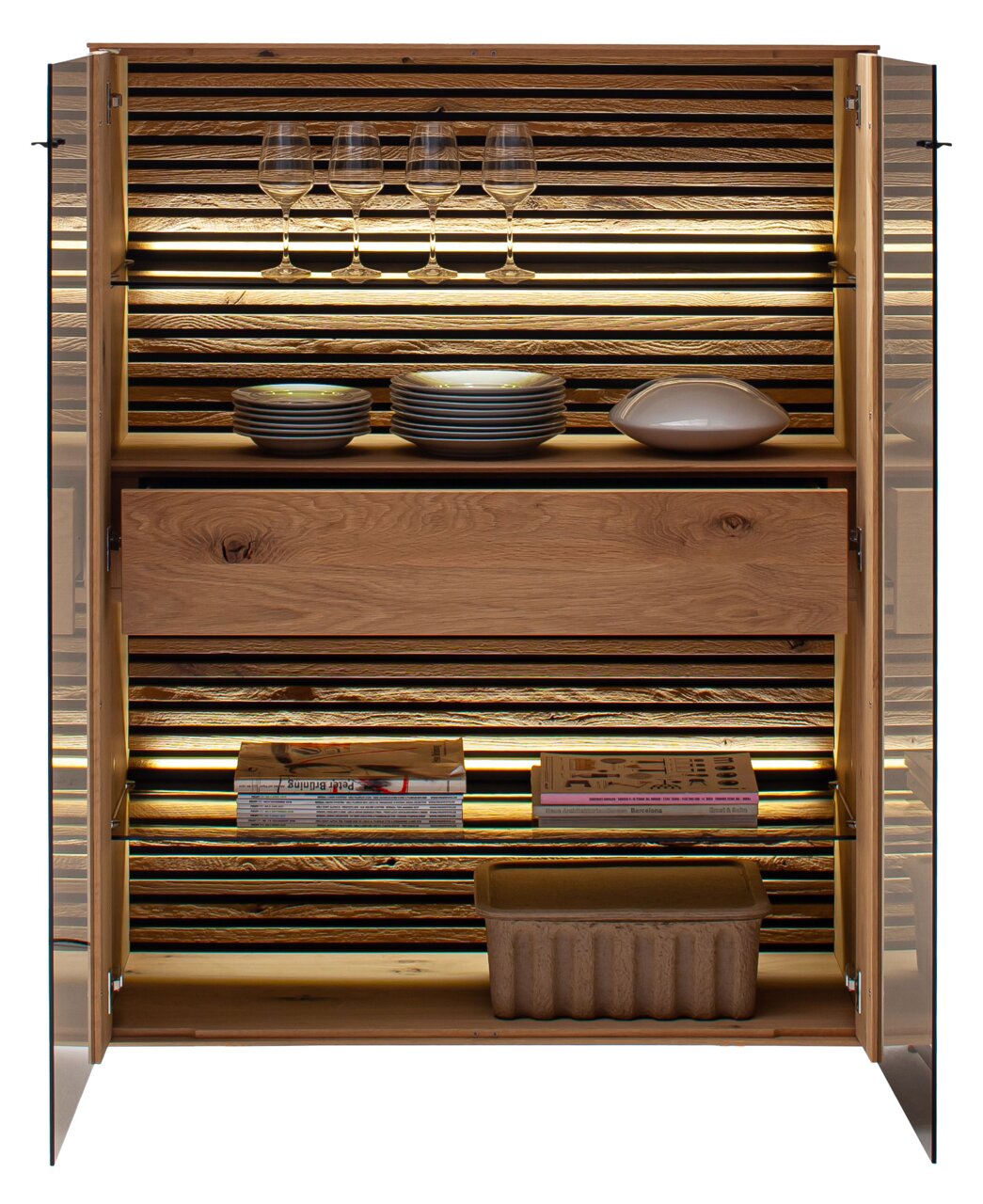 Open houten dressoir met glazen deuren, verlichte binnenkant, glazen, borden en boeken, gezien vanaf de voorkant.